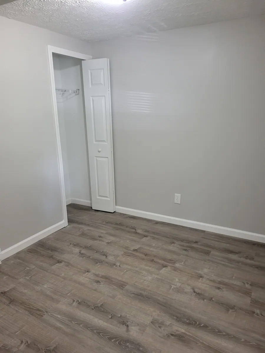 Unfurnished room in a two-bedroom unit with wood-look flooring and a closet