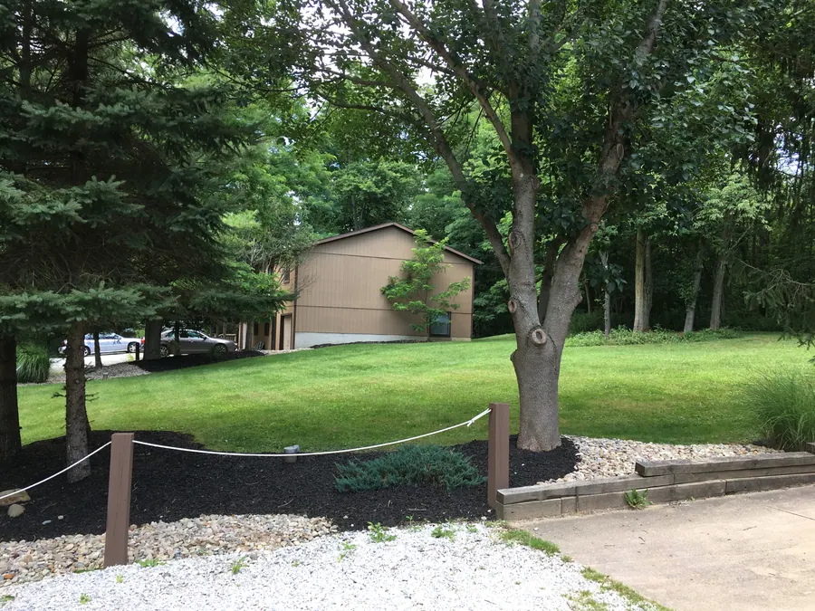 Lawn and mature trees surrounding a Hidden Pines townhome