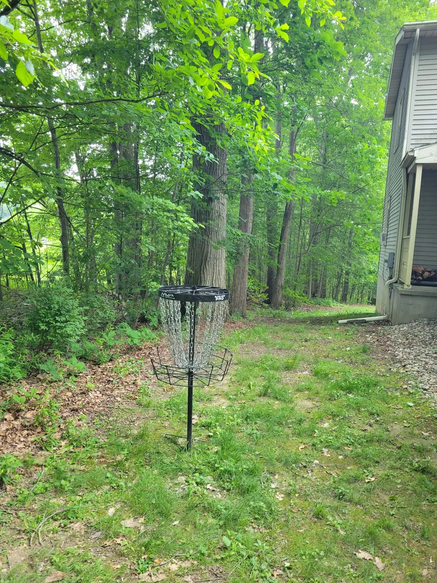 Wooded lawn beside a Hidden Pines townhome with a disc golf basket
